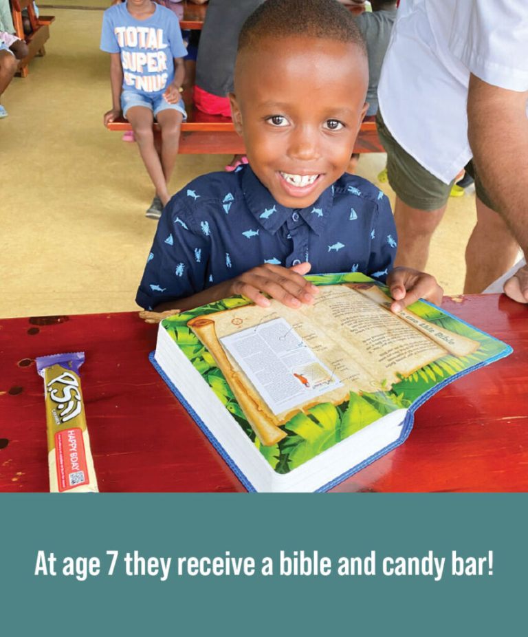 A child receiving a bible and candy bar for birthday.